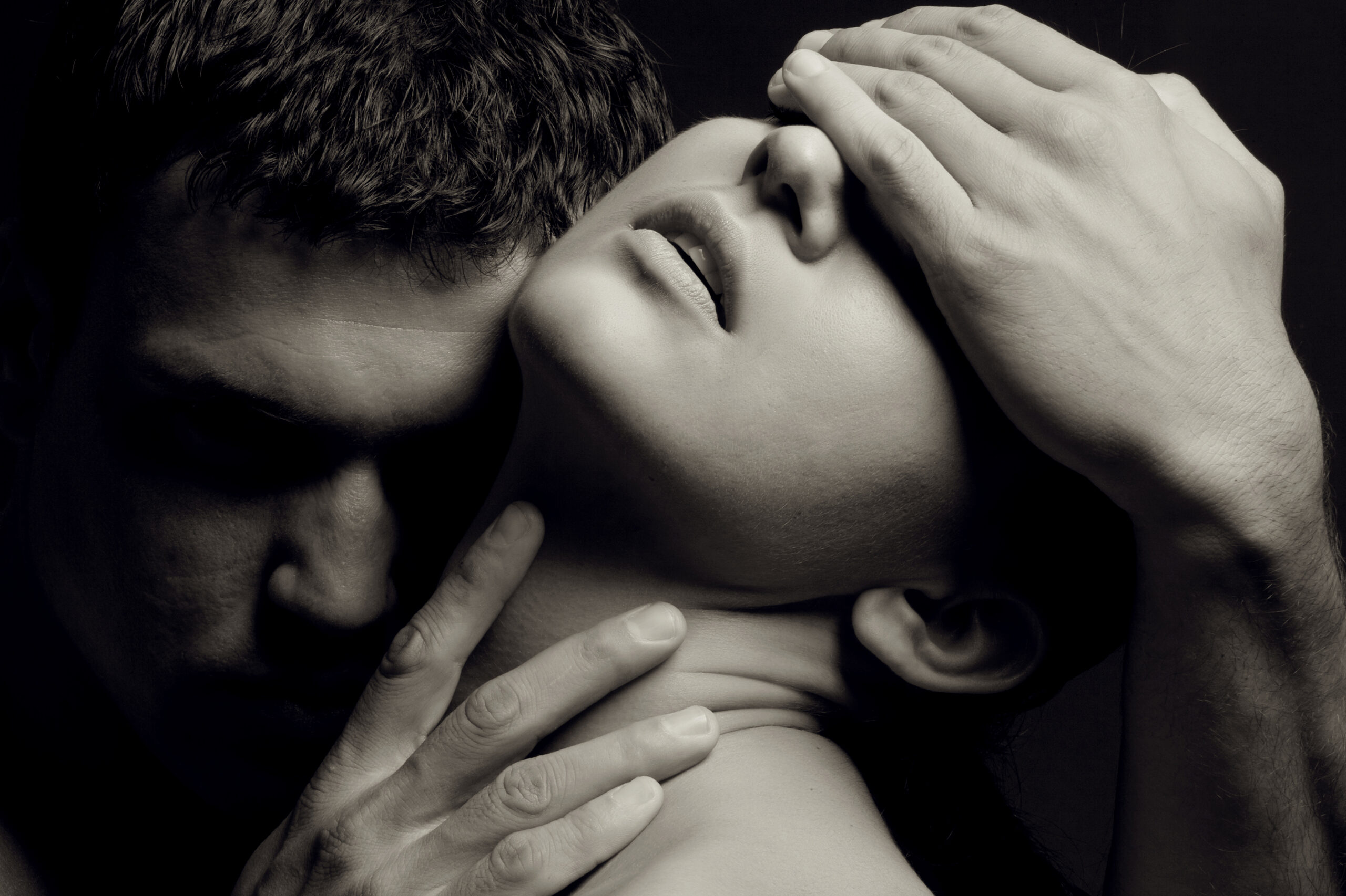 A man's hand cradling a woman's head and throat as she tilts back into his touch